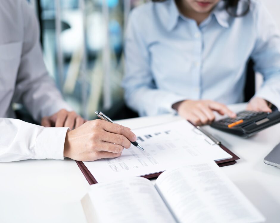 hommes écrivant sur une feuille et femme calculant sur calculatrice